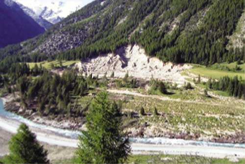 Dal punto di osservazione sopra l'abitato di Champlong vista generale sull'imponente movimento franoso. In primo piano l'alveo del torrente Urthier, il cui corso è stato interamente deviato; nella parte centrale la zona di accumulo caratterizzata dai larici inclinati e dalla cotica erbosa sconnessa; sullo sfondo la nicchia di distacco.