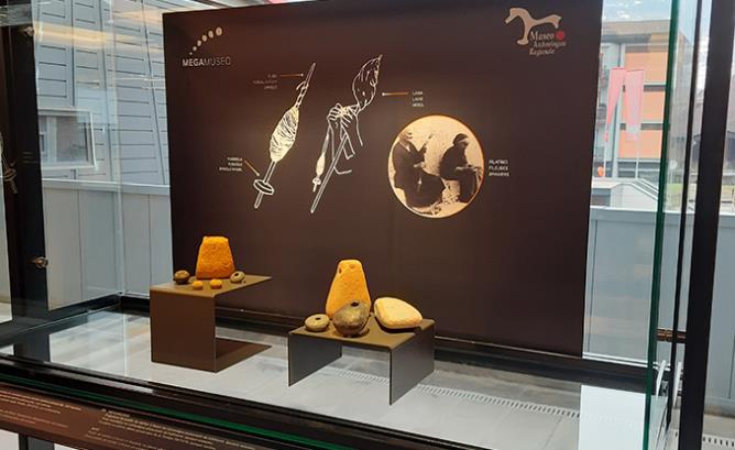 Vitrine du MegaMuseo avec, à gauche, des poids de métier à tisser provenant du site où se trouve l'espace d'exposition et, à droite, ceux des collections du MAR. Les descriptions des pièces exposées sont fournies ci-dessus.